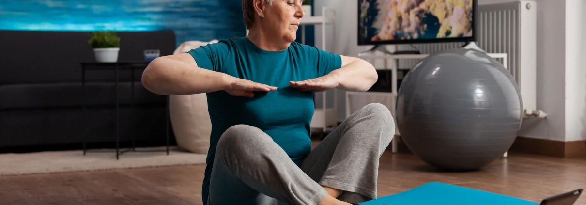 Senior suivant une vidéo de gym douce à la maison sur une chaise