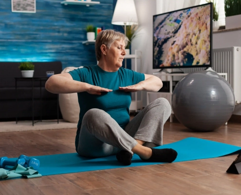 Senior suivant une vidéo de gym douce à la maison sur une chaise
