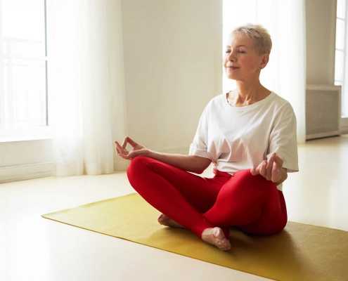 Senior pratiquant une séance de yoga sur chaise à domicile
