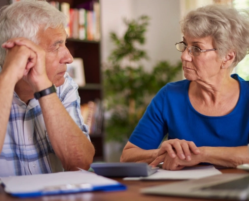 Couple de seniors comparant le prix d’une complémentaire santé avec une conseillère