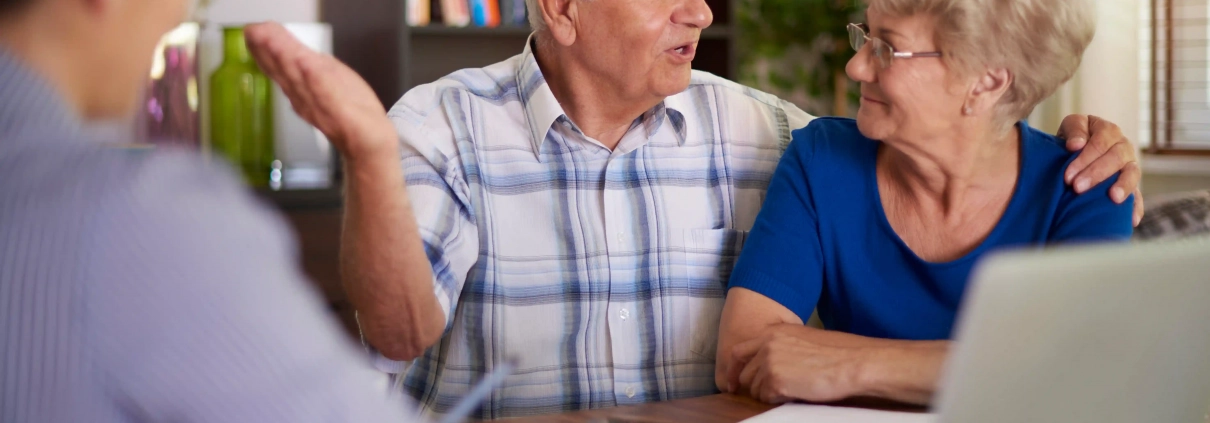 Couple de seniors comparant une complémentaire santé après 60 ans avec une conseillère