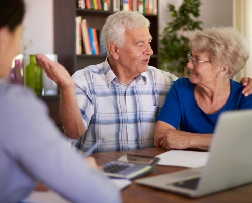 Couple de seniors comparant une complémentaire santé après 60 ans avec une conseillère