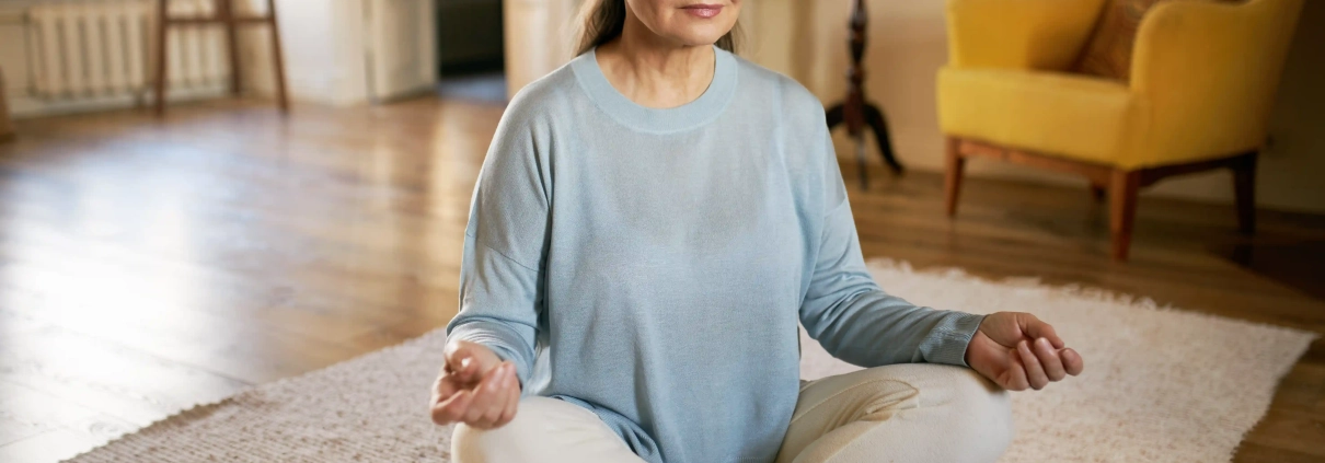 Femme senior pratiquant la relaxation et la méditation à domicile pour réduire son stress
