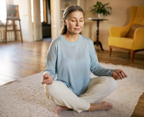 Femme senior pratiquant la relaxation et la méditation à domicile pour réduire son stress