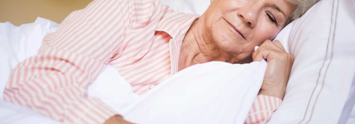 Femme senior dormant paisiblement dans sa chambre après avoir adopté de bonnes habitudes de sommeil.
