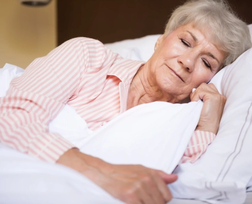 Femme senior dormant paisiblement dans sa chambre après avoir adopté de bonnes habitudes de sommeil.