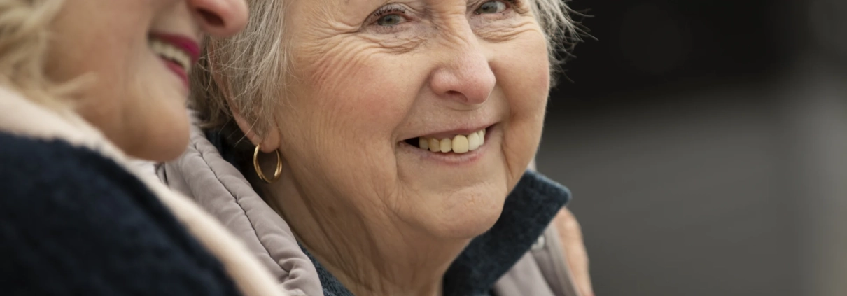 Deux femmes seniors souriantes discutent ensemble.