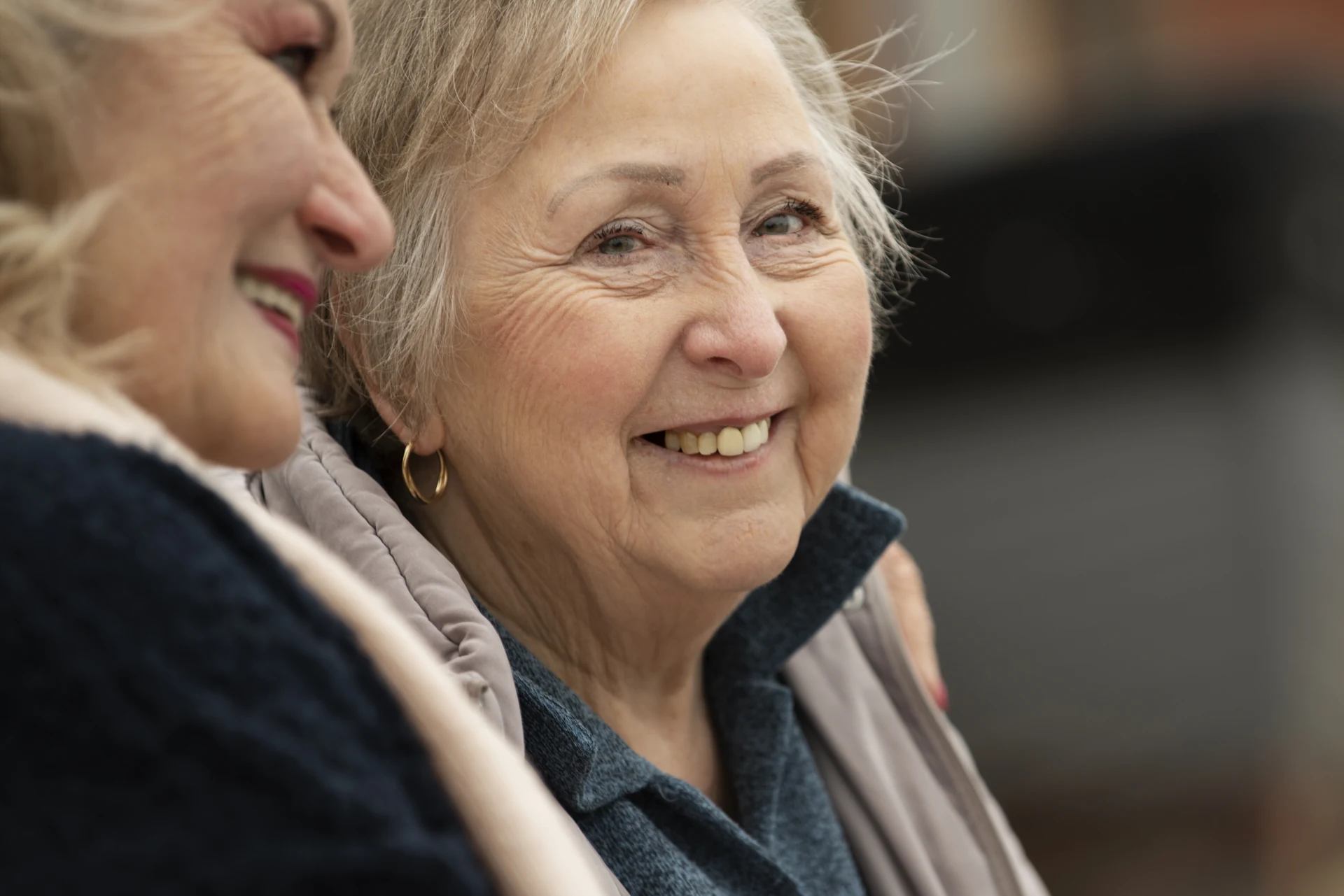 Deux femmes seniors souriantes discutent ensemble.